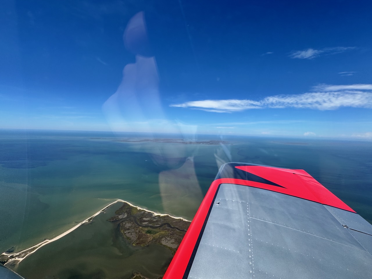 Tangier Island seen from the air beyond the red wingtip of an RV.