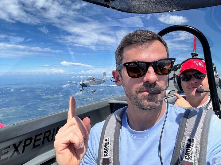 Two people in an RV cockpit with another airplane flying in formation outside.